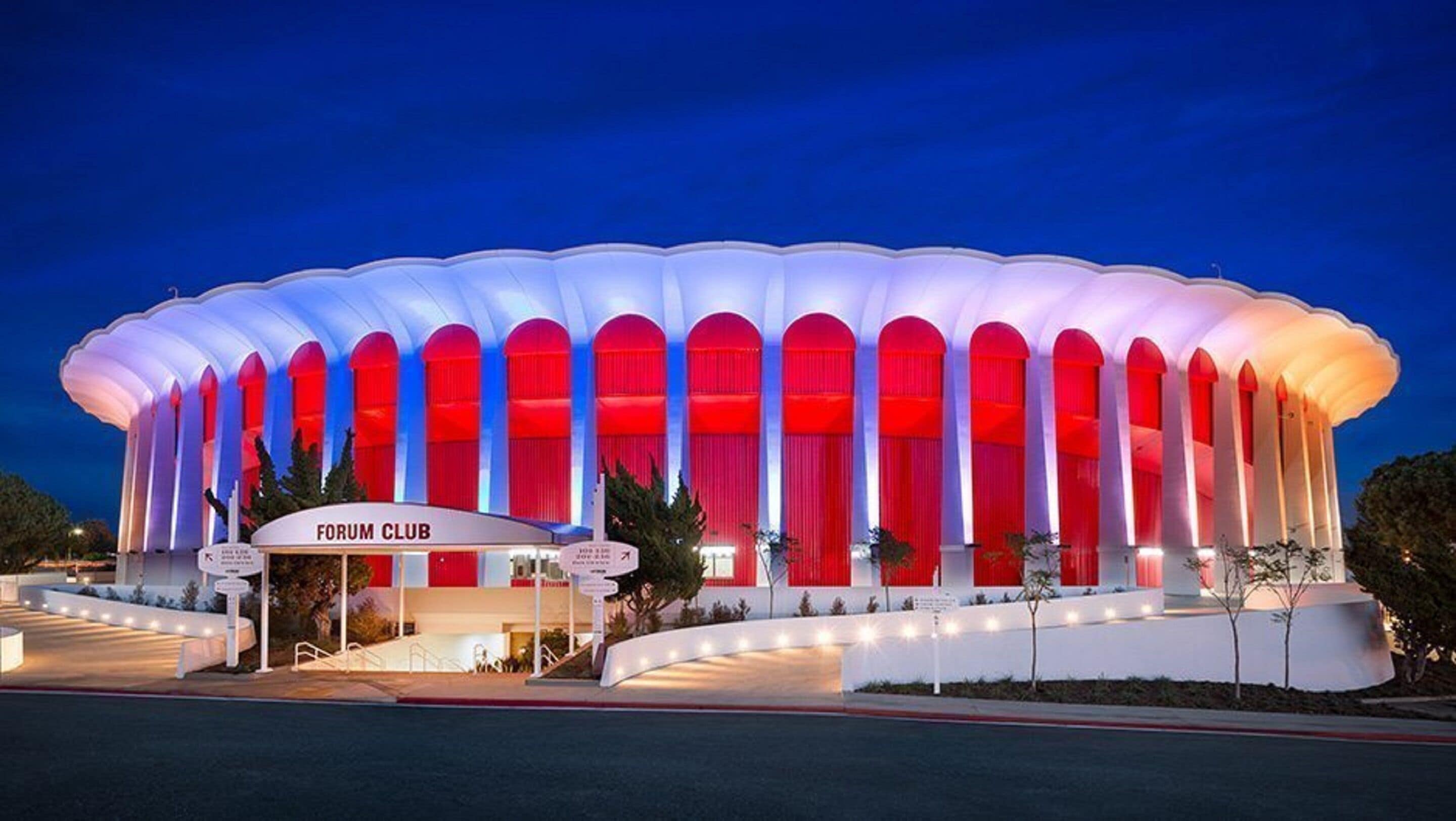 A large, modern building with a distinctive white and red color scheme, featuring a prominent entrance and a sign that reads "FORUM CLUB".