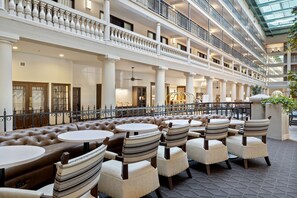 A multi-level atrium with a seating area featuring round tables and striped chairs.