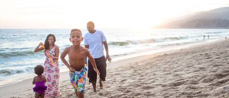 A family walking on a sandy beach with the ocean in the background.