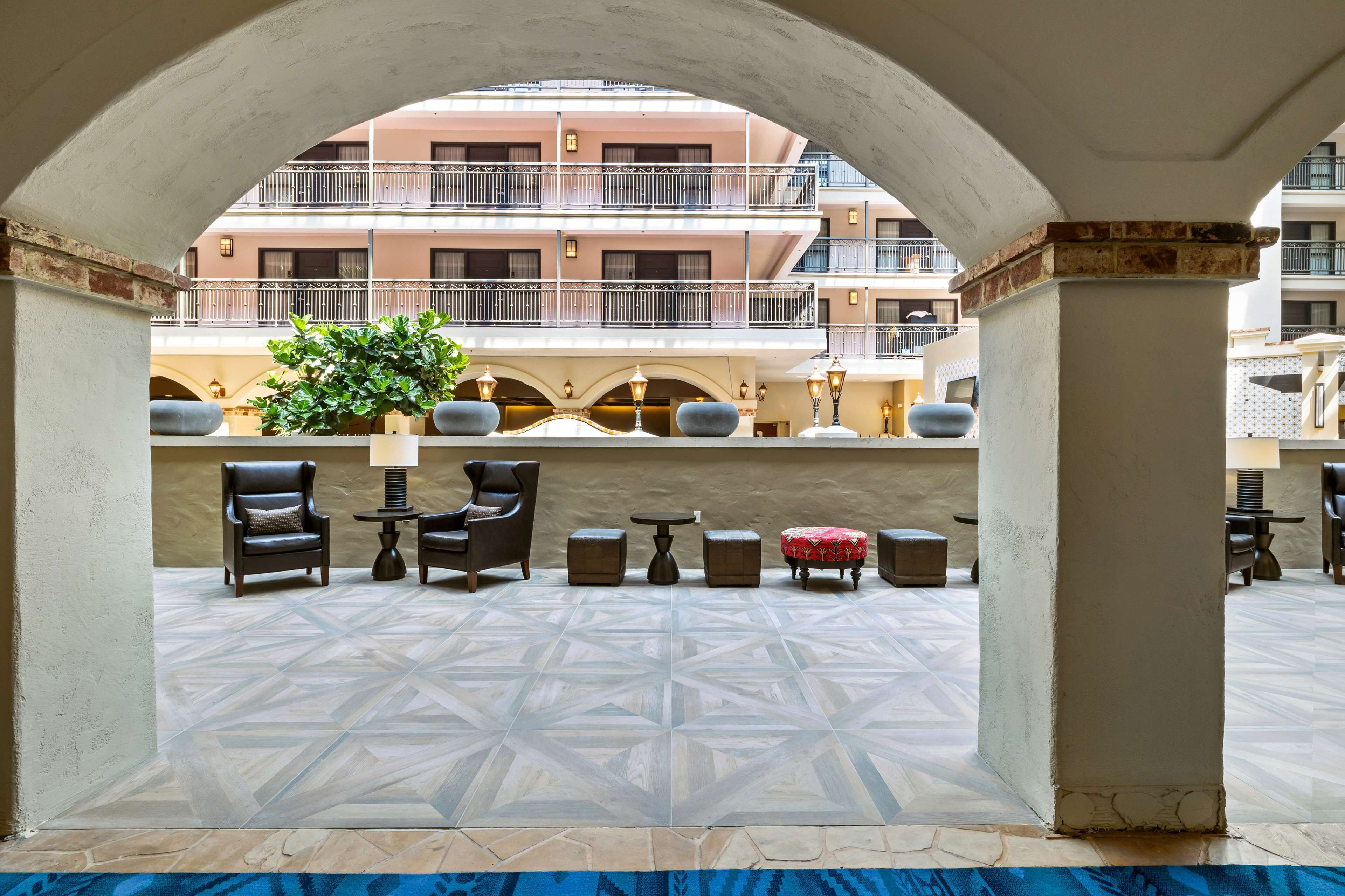 An outdoor seating area with a geometric tile floor, a potted plant, and a view of a multi-story building with balconies.