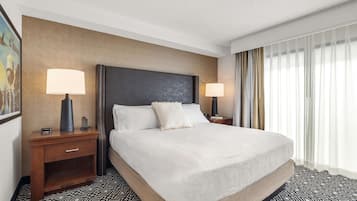 Habitación de hotel con una cama grande, dos mesitas de noche con lámparas, un cabecero y un piso con diseño.