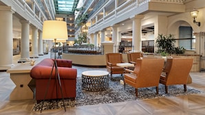 Un hall d’entrée spacieux, doté d’un plafond haut, de plusieurs niveaux et d’un espace de détente central avec une table ronde et des chaises.