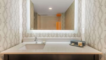 A bathroom with a large mirror, a sink, and a shower area.