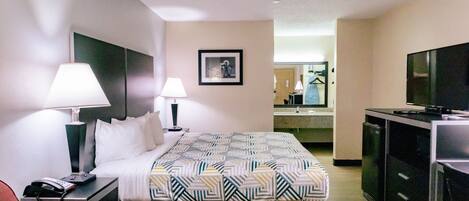 A hotel room with a bed, two bedside lamps, a telephone, a television, and a mirror.