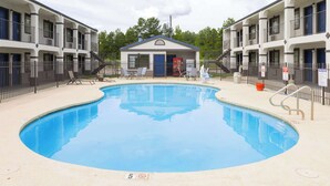 A swimming pool with lounge chairs and a small building in the background. - Motel 6 Nacogdoches TX (Nacogdoches)