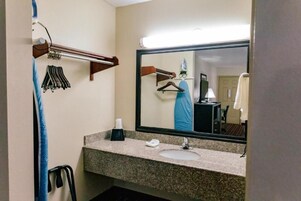 Un baño con encimera de granito, un lavamanos, un espejo y un perchero para toallas.