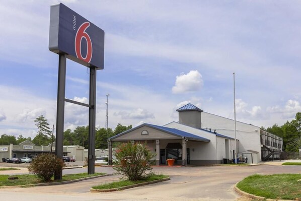 A motel with a prominent '6' sign, a covered parking area, and a building with a blue roof.