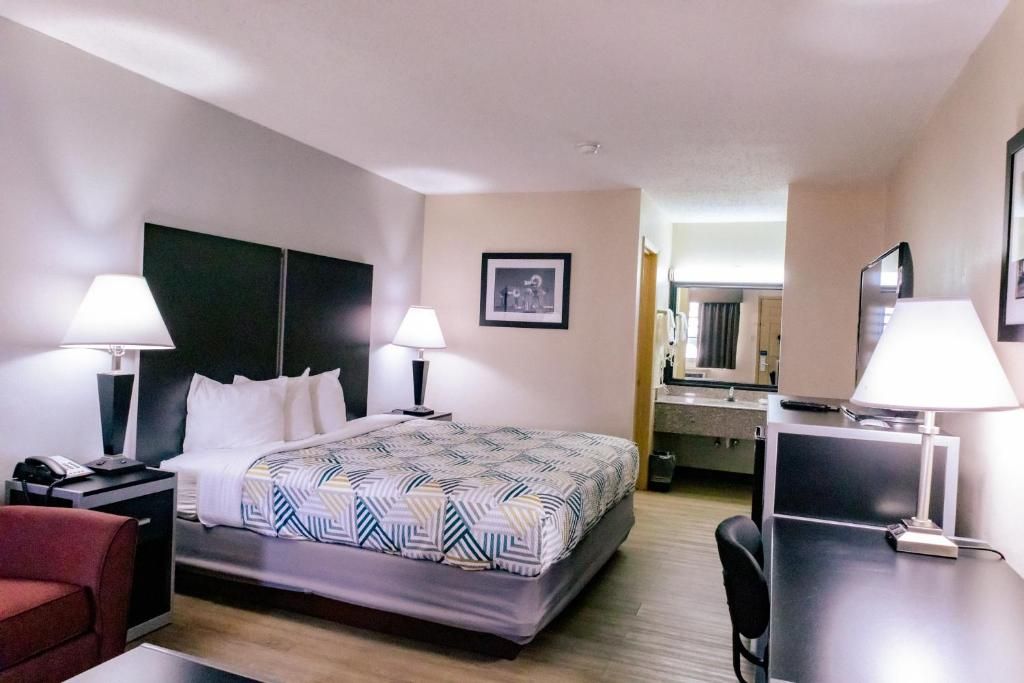 Una camera d'albergo con un letto, comodini, una scrivania, una sedia e uno specchio.