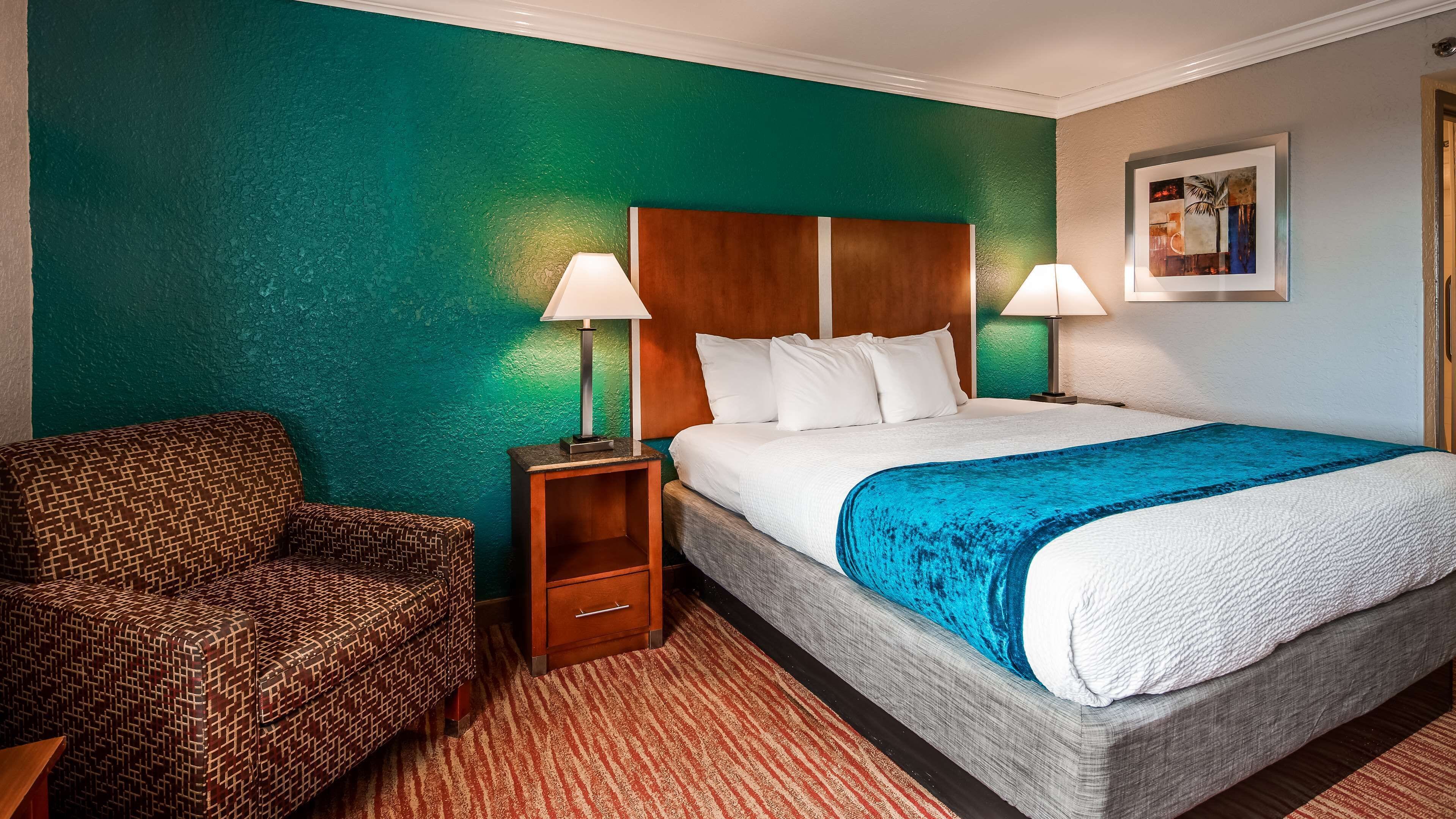 A hotel room with a bed, a chair, and a nightstand.
