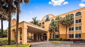 Un hotel Best Western con entrada cubierta, palmeras y aparcamiento.