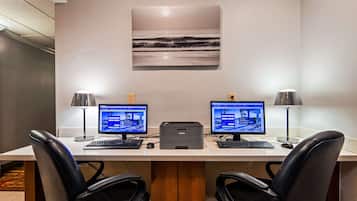A workspace with two monitors, a printer, and two chairs.