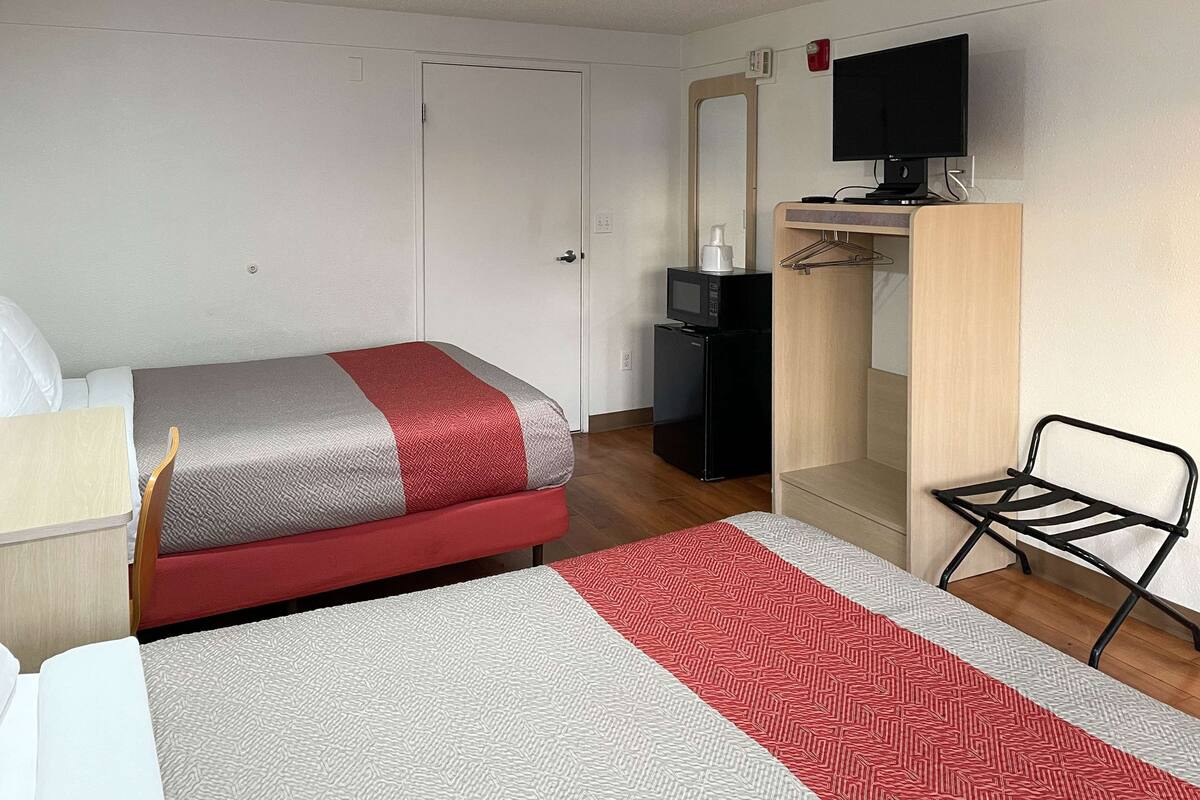 Ein Hotelzimmer mit Bett, Schreibtisch, Fernseher und Kleiderschrank.