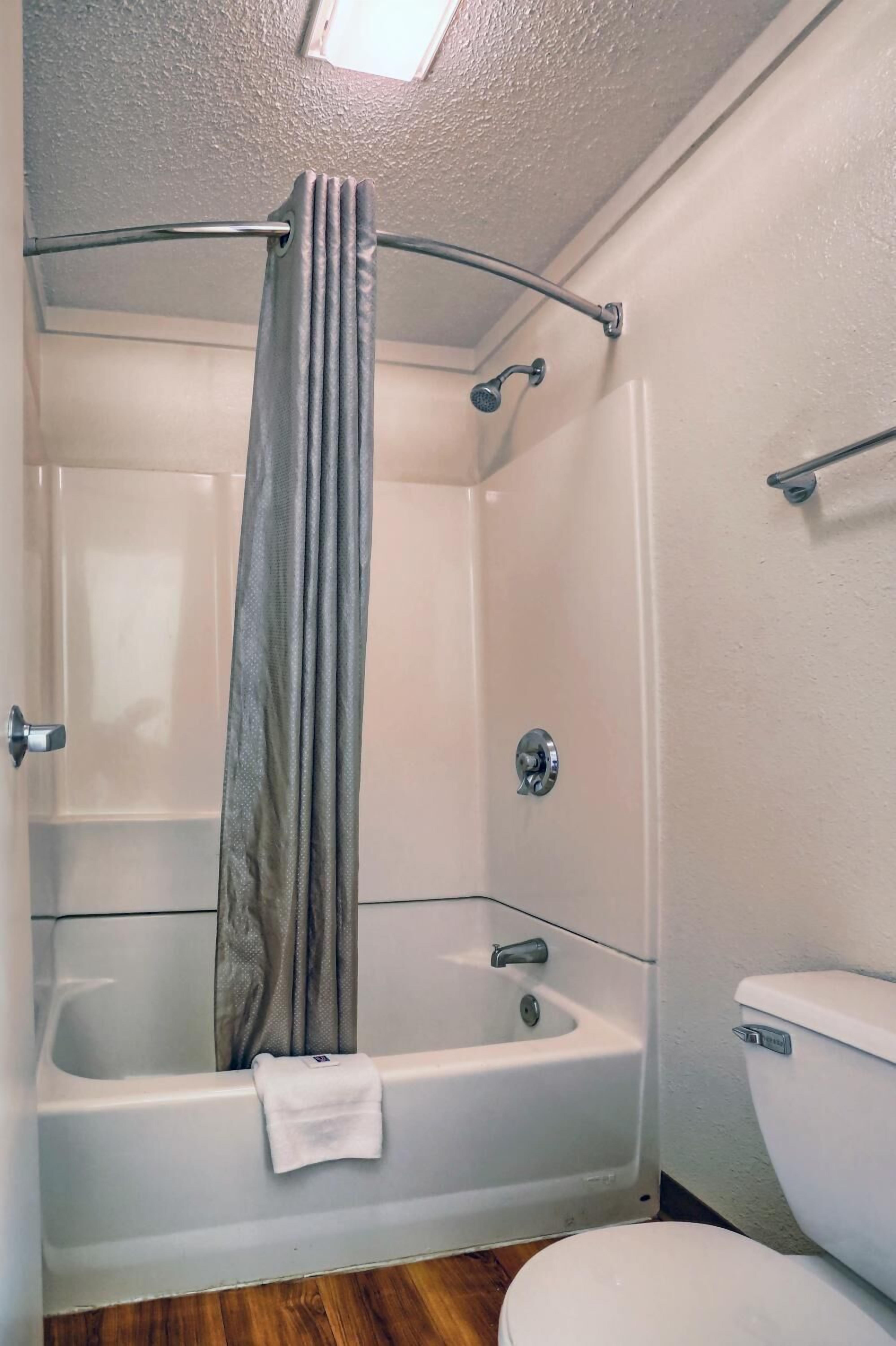 A bathroom with a bathtub, shower, and toilet.