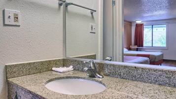 A bathroom with a granite countertop sink, a mirror, and a towel rack.