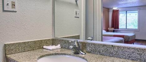 A bathroom with a granite countertop sink, a mirror, and a towel rack.