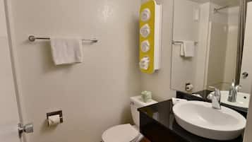 Ein Badezimmer mit Toilette, Waschbecken, Spiegel, Handtuchhalter und einem gelben Handtuchwärmer.