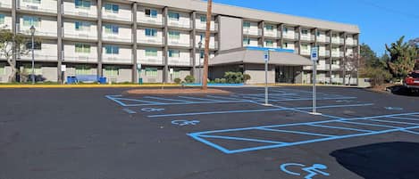 Um parque de estacionamento com vagas para pessoas com deficiência e um edifício com vários andares e varandas.
