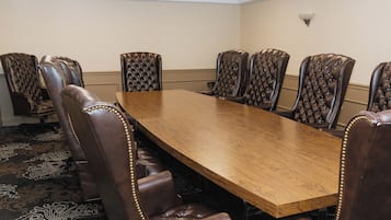 Una sala de conferencias con una larga mesa de madera y seis sillas de cuero con respaldo alto.