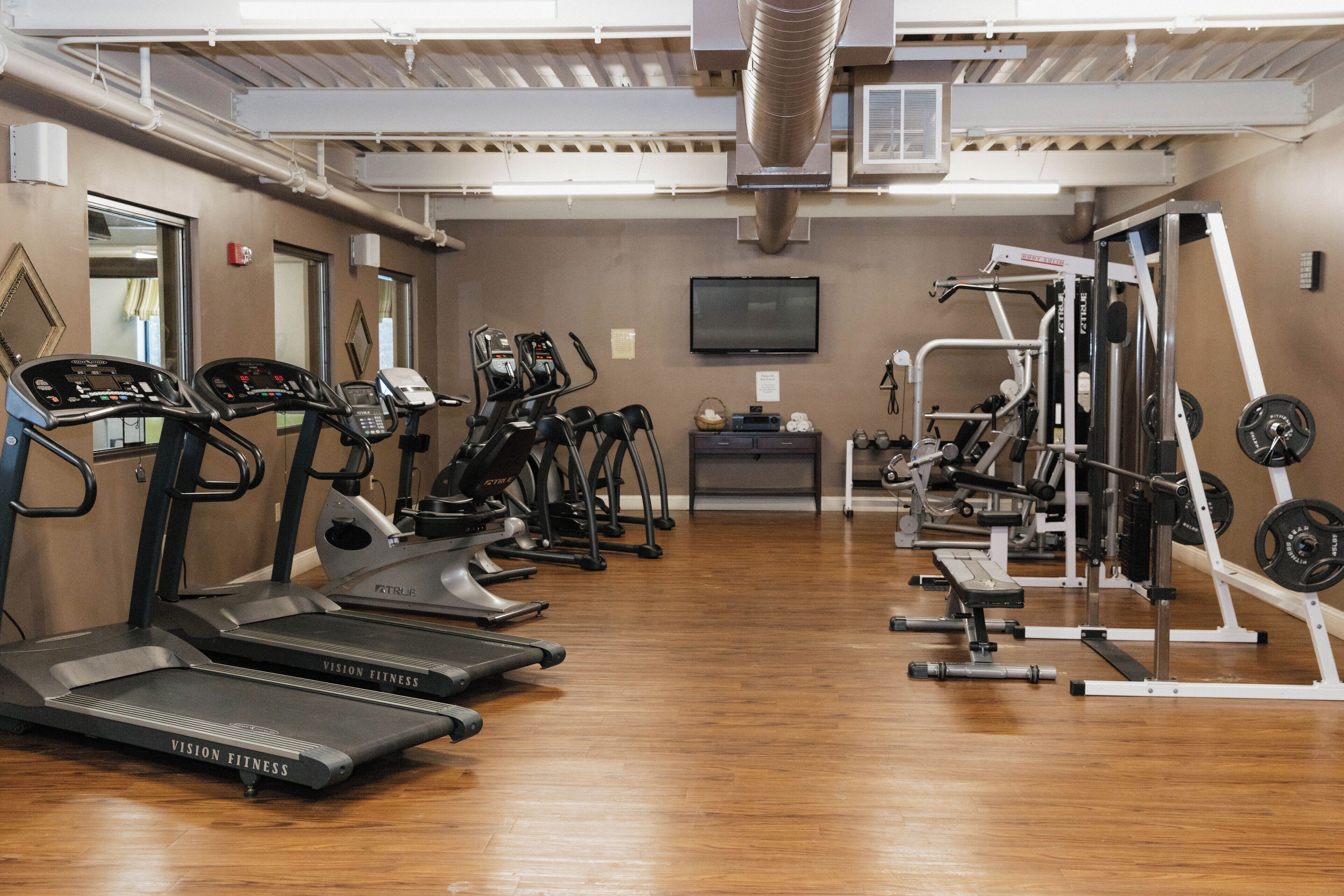 Un gimnasio con cintas de correr, elípticas y equipos de levantamiento de pesas.