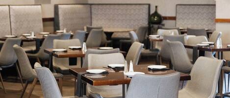 A hotel dining area with booths and tables, featuring a modern design with wooden accents and neutral color palette.