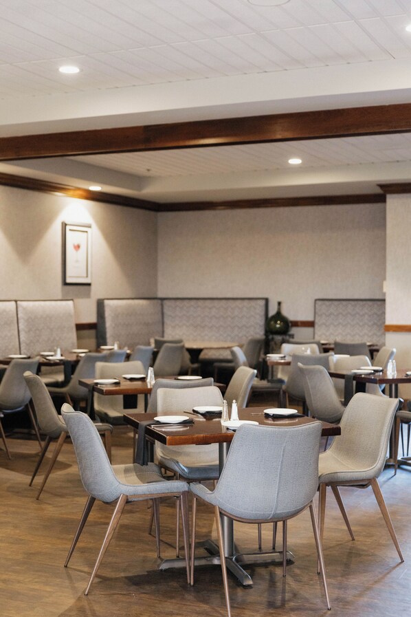 A hotel dining area with booths and tables, featuring a modern design with wooden accents and neutral color palette.