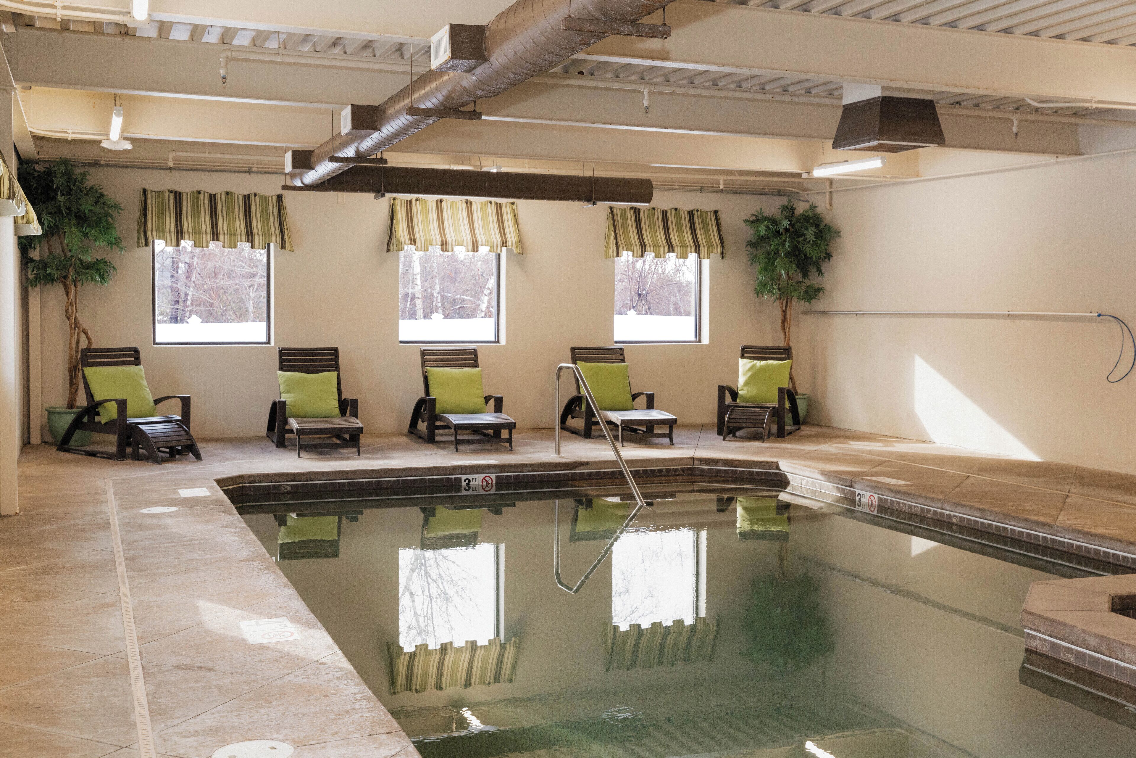 A swimming pool with lounge chairs and potted plants.