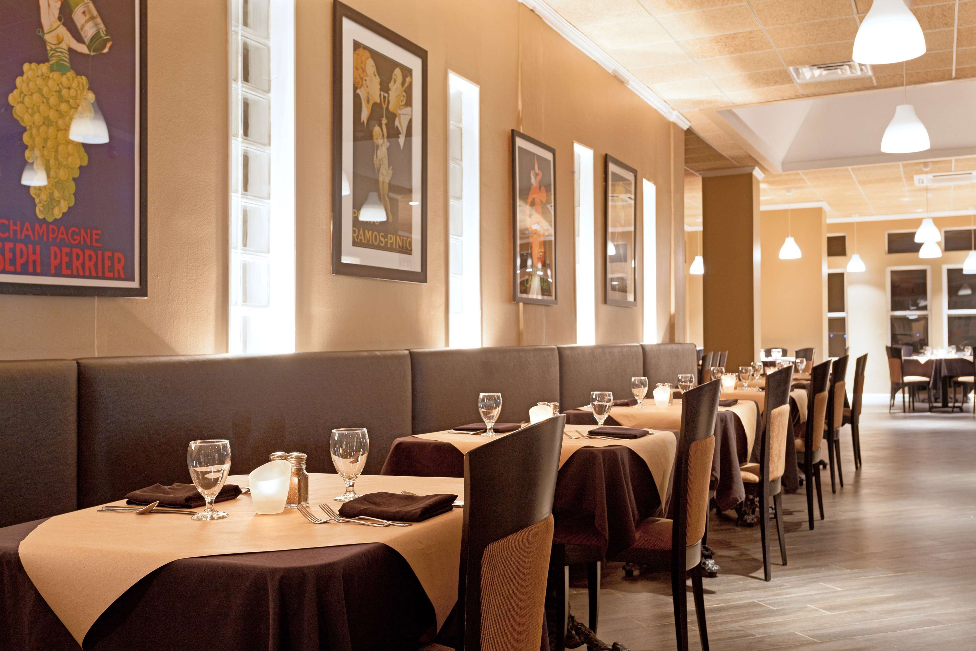 A restaurant with booths and tables, each set with wine glasses, cutlery, and napkins.