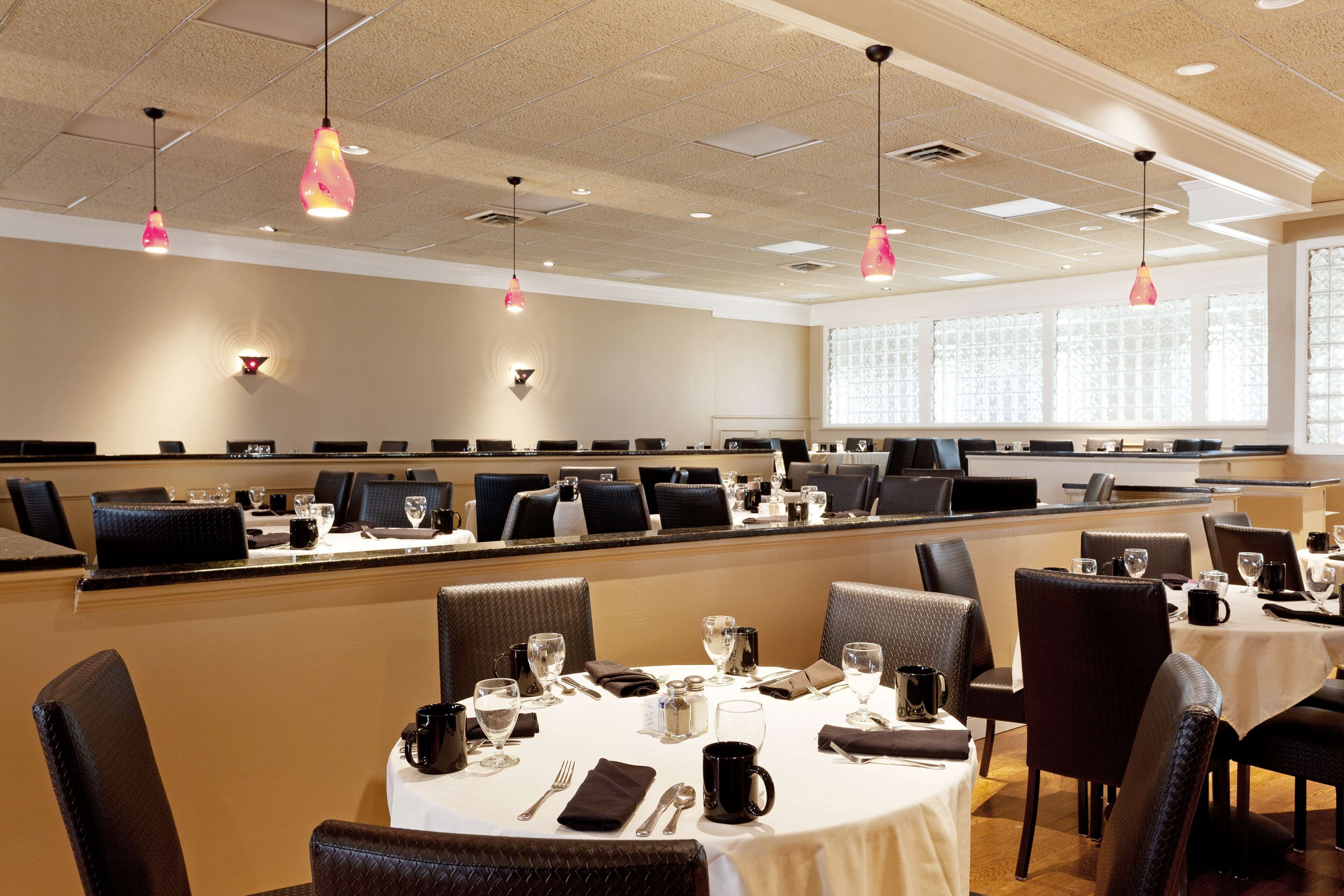 A conference room with multiple tables, chairs, and a long counter.