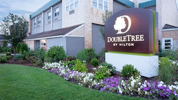 Placa DoubleTree by Hilton com um jardim ajardinado na frente.
