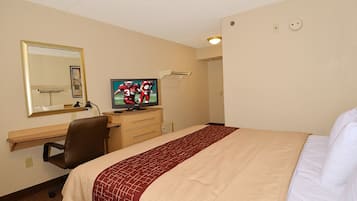 A hotel room with a bed, a desk with a computer, a television, and a mirror.
