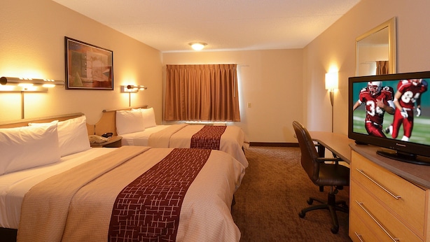A hotel room with two beds, a desk, a television, and a window with curtains. - Red Roof Inn San Antonio - Airport (San Antonio)