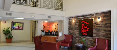 A Red Roof Inn lobby with a seating area, a kitchenette, and a view of the upper floor.