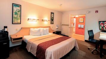 A hotel room with a bed, bedside tables, a desk with a chair, and a television.