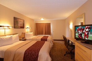 A hotel room with two beds, a desk, a television, and a mirror. - Red Roof Inn San Antonio - Airport (San Antonio)