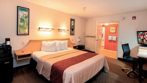 Quarto de hotel com uma cama grande, mesas de cabeceira, uma escrivaninha com cadeira e uma televisão.