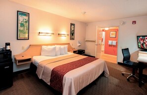 A hotel room with a large bed, bedside tables, a desk with a chair, and a television. - Red Roof Inn San Antonio - Airport (San Antonio)
