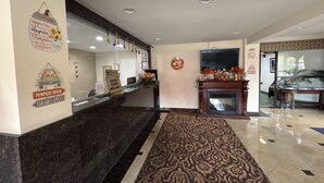 A hotel reception area with a marble counter, a fireplace, and seasonal decorations.