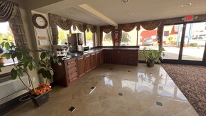 A spacious lobby with a polished tile floor, a reception desk, and a large window offering a view of the street.