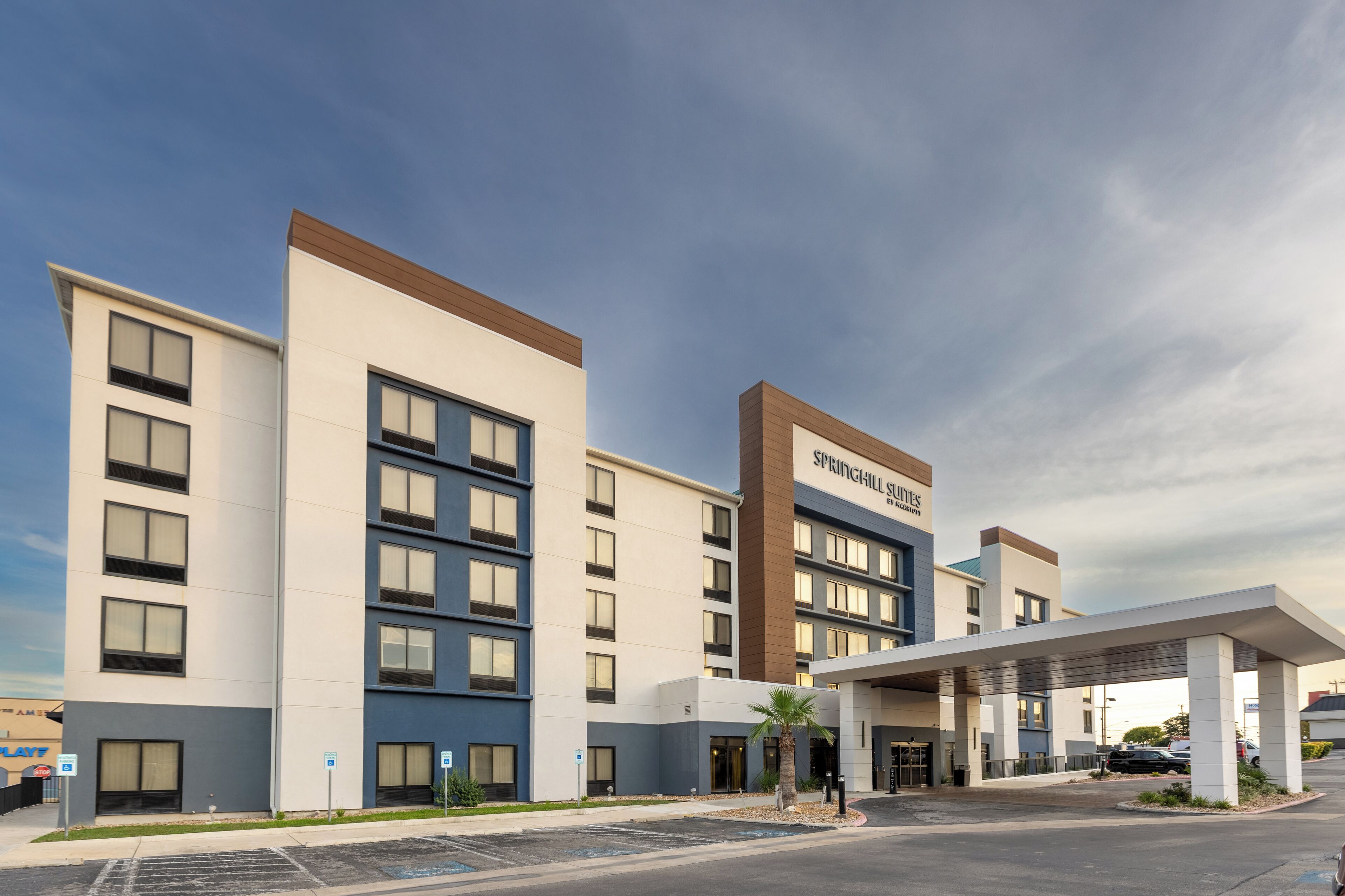 A modern hotel with a flat roof, multiple floors, and a prominent entrance with a covered area.