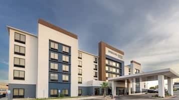 A modern hotel with a flat roof, multiple floors, and a prominent entrance with a covered area.