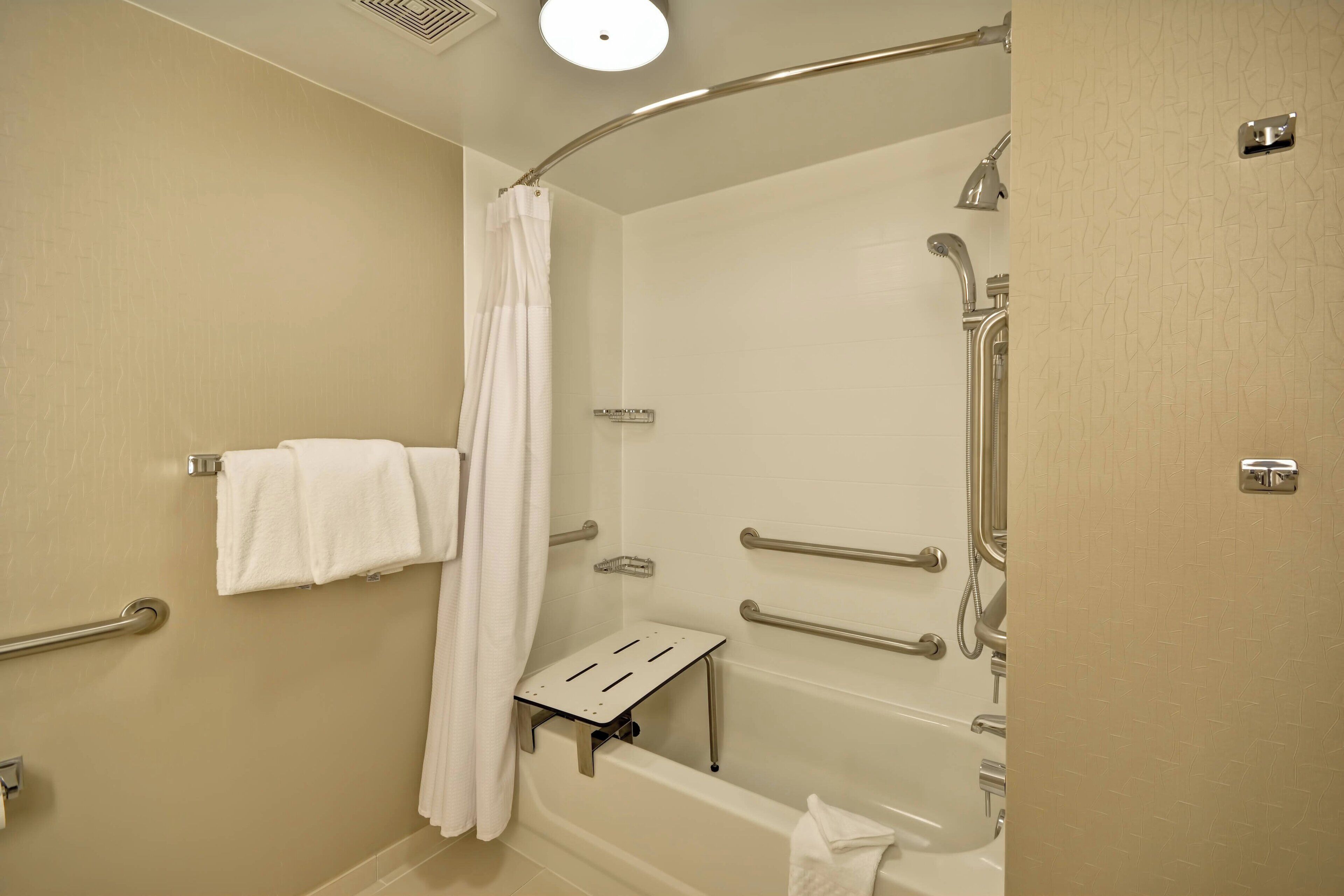 A modern bathroom with a walk-in shower, grab bars, a towel rack, and a shower curtain.