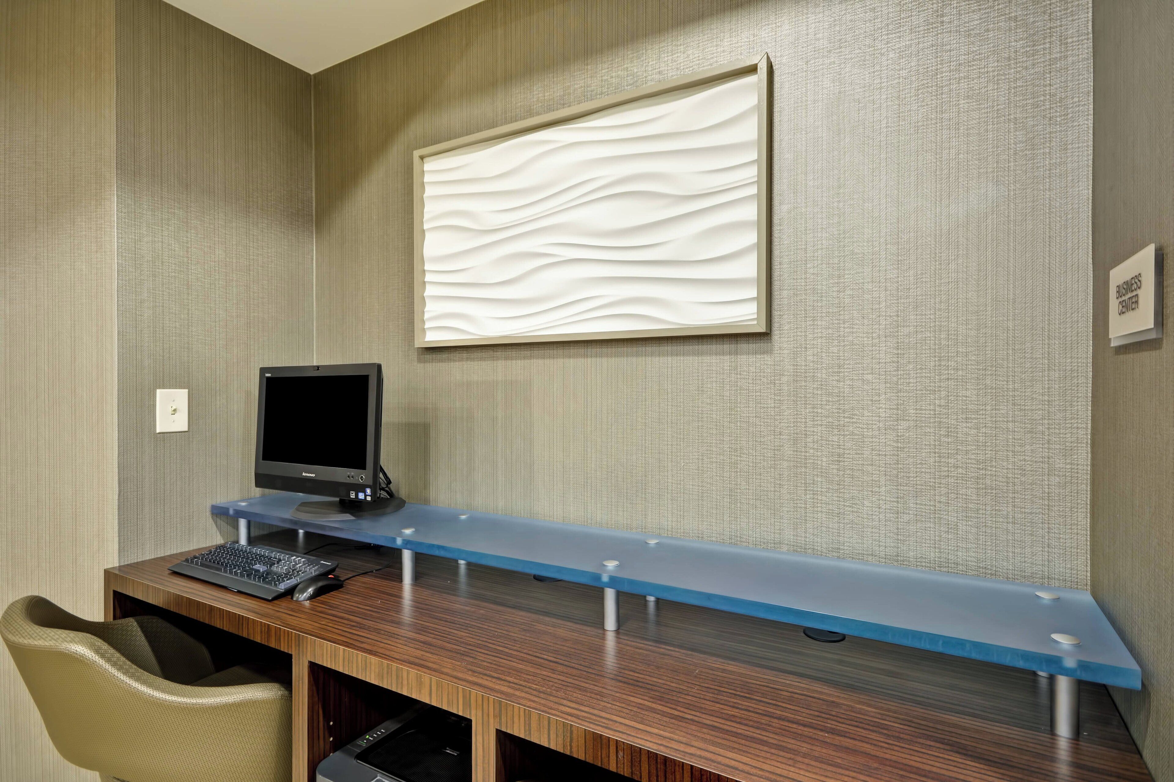 A modern office space with a long desk, a computer, and a chair.