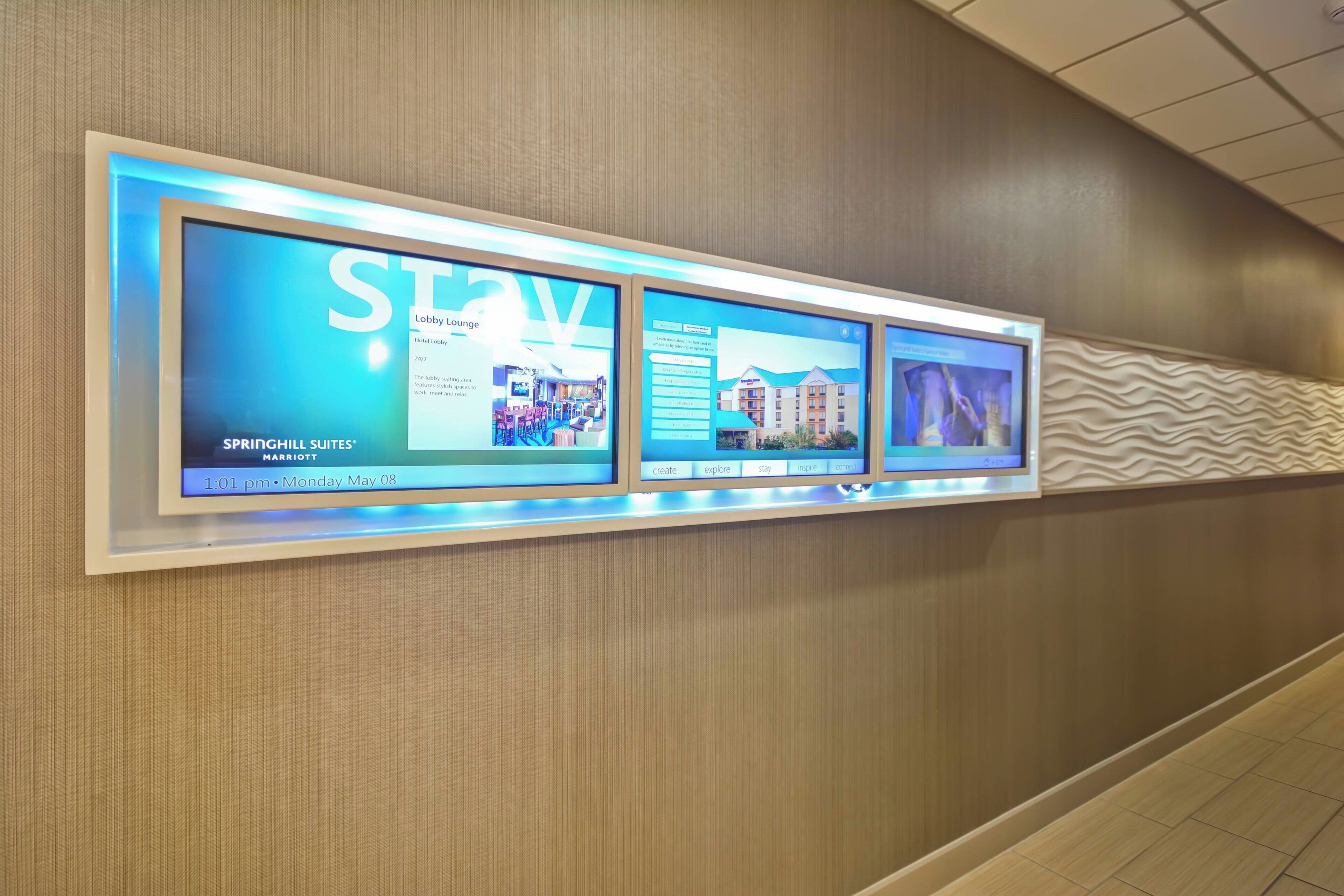 A digital display in a hotel lobby advertising Springhill Suites Marriott with a modern design and a textured wall.
