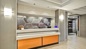 A reception area with a modern design, featuring a counter with a digital display, a decorative hexagonal wall, and a clean, tiled floor.