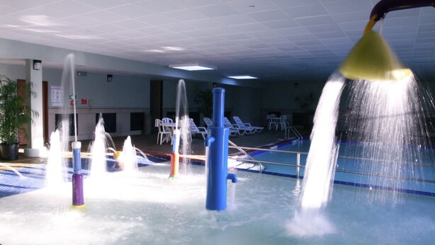 An indoor water play area with multiple fountains and a pool. - Rodeway Inn (Portage)