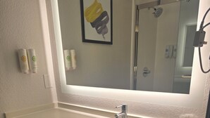 A bathroom with a sink, mirror, towel rack, and toilet paper. - Rodeway Inn (Portage)