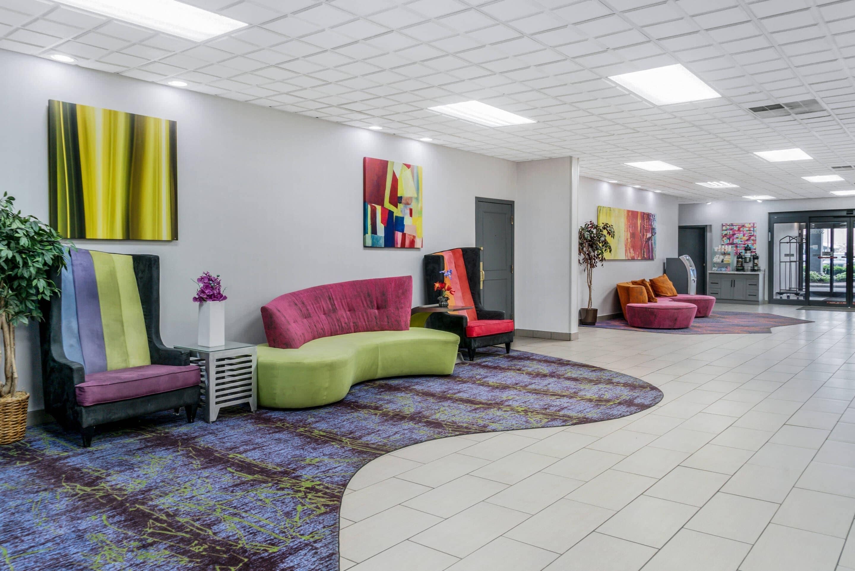 A modern lobby with a curved seating area, a reception desk, and colorful artwork on the walls.