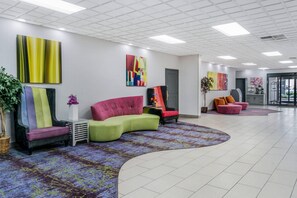A modern lobby with a curved seating area, a reception desk, and colorful artwork on the walls.