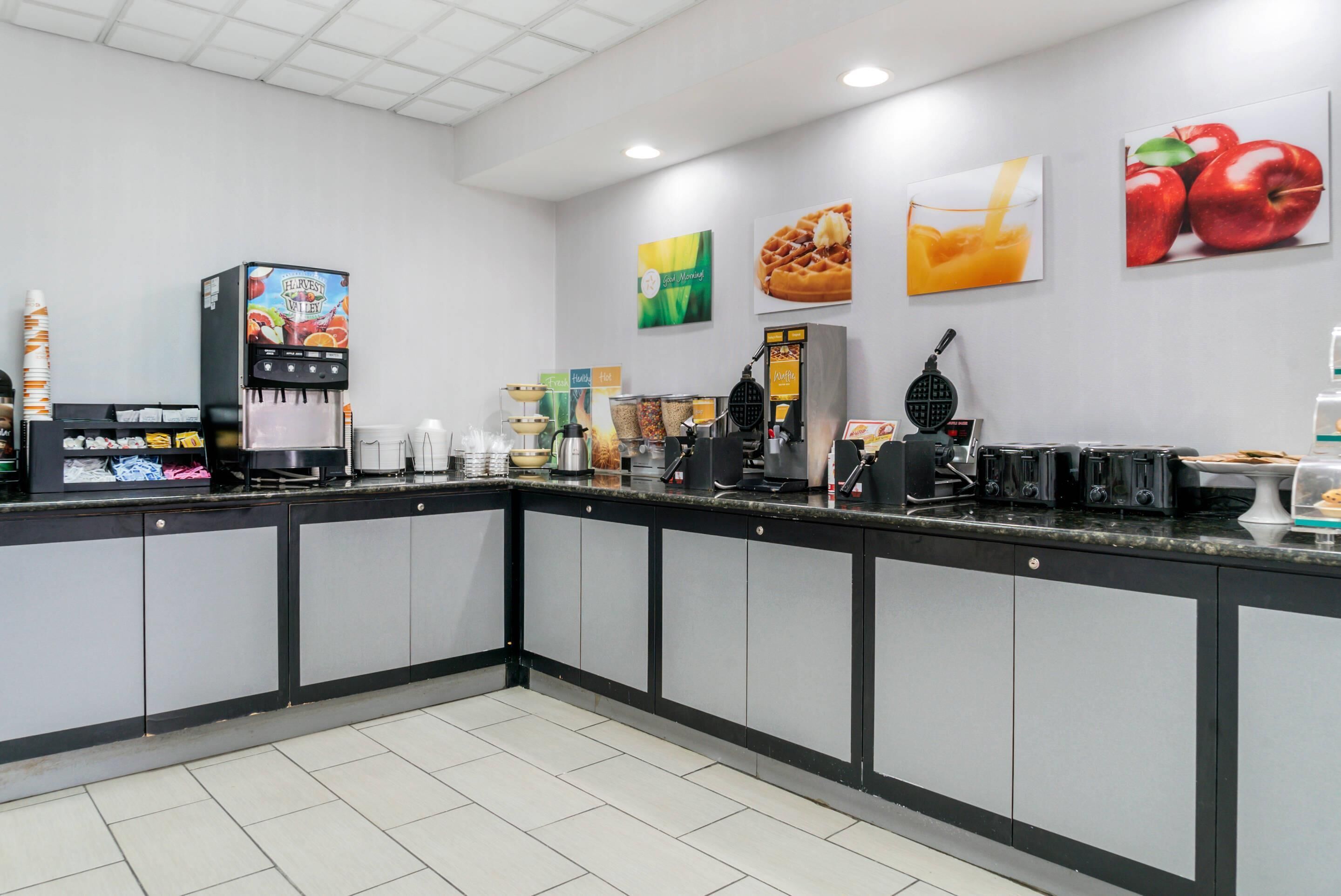 A clean, modern cafe with a self-serve coffee station, a waffle maker, and various food items on display.
