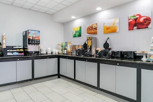 A clean, modern cafe with a self-serve coffee station, a waffle maker, and various food items on display.